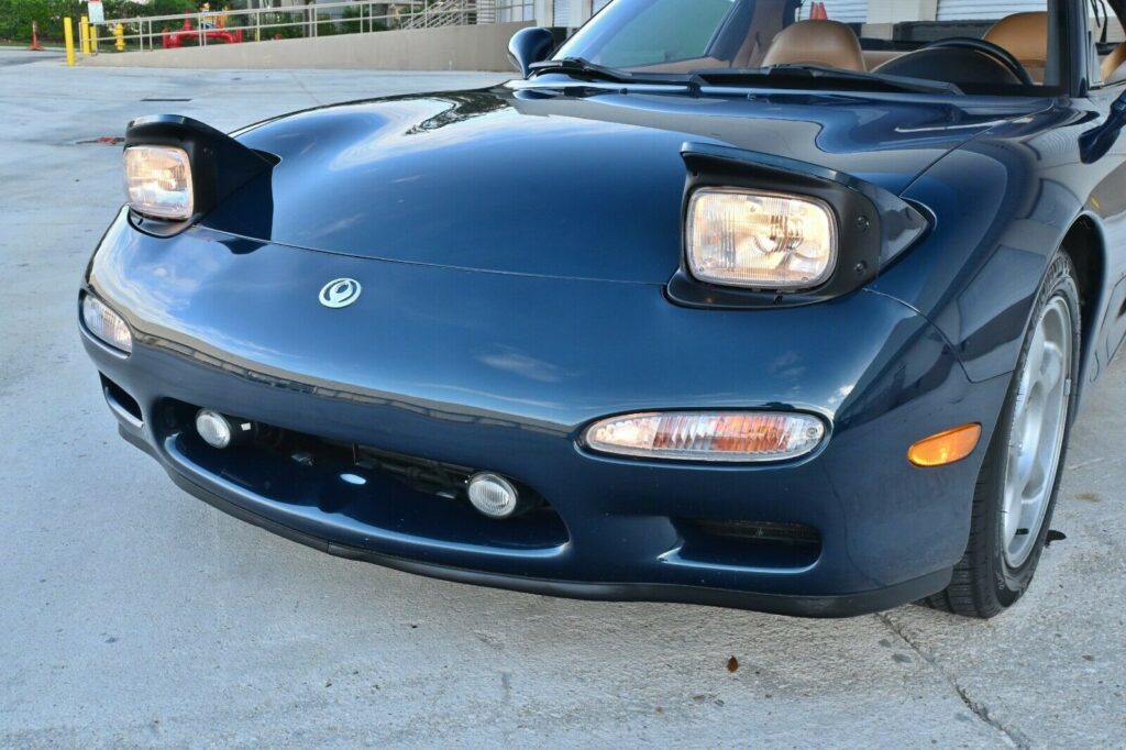 Front angle view of Montego Blue 1993 Mazda RX-7 Touring with pop-up headlights raised