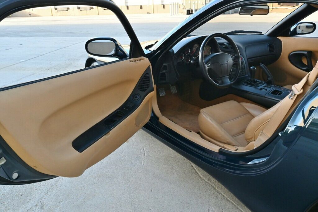 Opened driver's door and cockpit of Montego Blue 1993 Mazda RX-7 Touring 