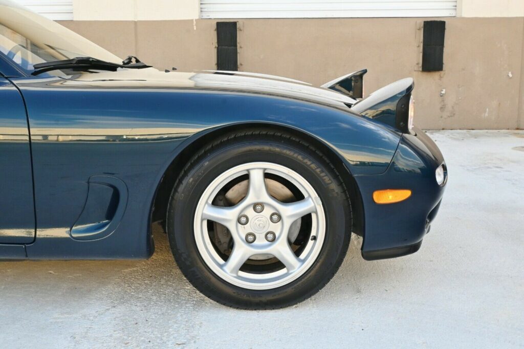 Side view of Montego Blue 1993 Mazda RX-7 Touring with pop-up headlights raised