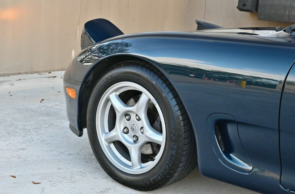 Front wheel and pop-up headlights on Montego Blue 1993 Mazda RX-7 Touring 