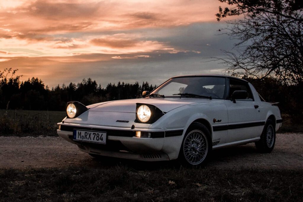 White Mazda FB RX-7 with pop-up headlights at sunset